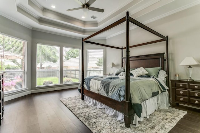 bedroom featuring a tray ceiling, ornamental molding, dark wood-type flooring, and a ceiling fan