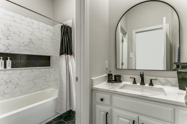 full bath featuring vanity, shower / bath combination with curtain, a textured wall, and tile patterned flooring