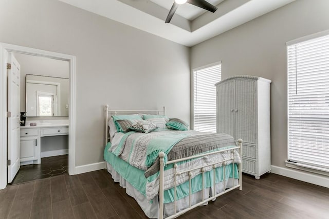 bedroom featuring dark wood-style flooring, baseboards, ensuite bathroom, and a ceiling fan