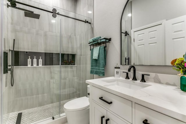 bathroom featuring toilet, a stall shower, and vanity