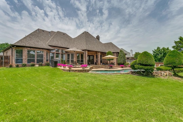 rear view of house featuring brick siding, a patio, an outdoor pool, and a chimney