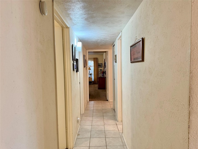 7302 Hardwood Trl, Dallas, TX 75249 - hallway featuring light tile patterned floors, a textured ceiling, a textured wall, and baseboards