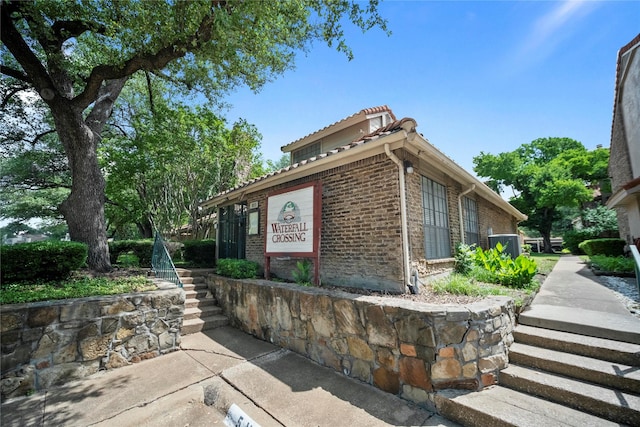 895 Dublin Dr Unit D, Richardson, TX 75080 - view of property exterior featuring stairs, brick siding, and a tiled roof