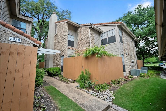 895 Dublin Dr Unit D, Richardson, TX 75080 - view of side of property with a chimney, a tiled roof, fence, and stone siding