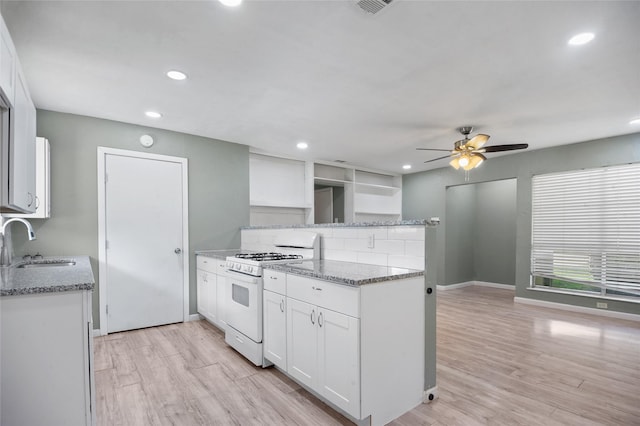 2500 Bamboo St, Mesquite, TX 75150 - kitchen with white gas range oven, a sink, a peninsula, white cabinetry, and a ceiling fan