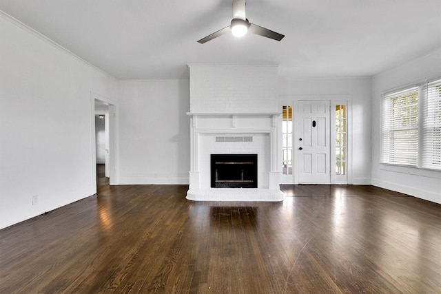 unfurnished living room featuring ceiling fan, a brick fireplace, wood finished floors, ornamental molding, and baseboards