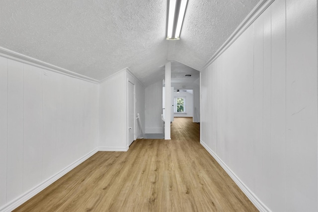 additional living space with light wood-style flooring, a textured ceiling, and lofted ceiling