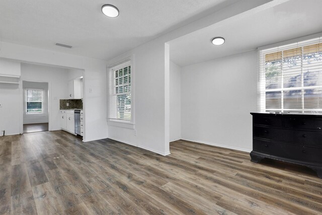 unfurnished living room featuring dark wood-style flooring and baseboards