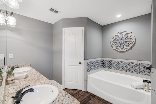 160 Grays Creek Cir, Alma, TX 75119 - full bathroom featuring wood finished floors, a bath, double vanity, and a chandelier