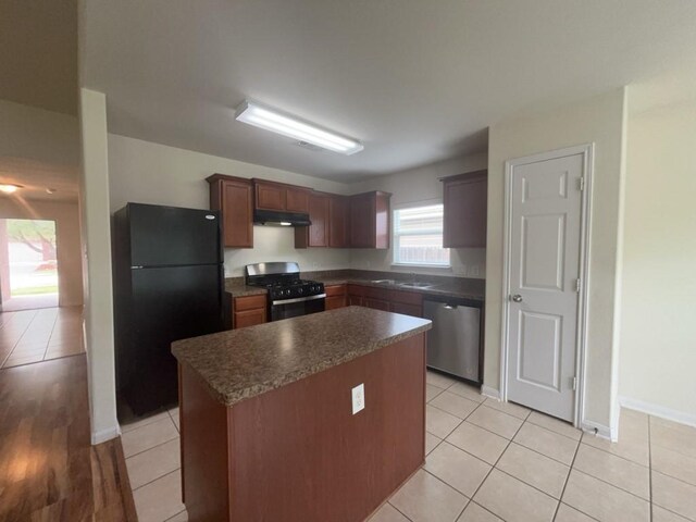 10009 Iron Ridge Dr, Fort Worth, TX 76140 - kitchen with black appliances, under cabinet range hood, a sink, dark countertops, and a kitchen island