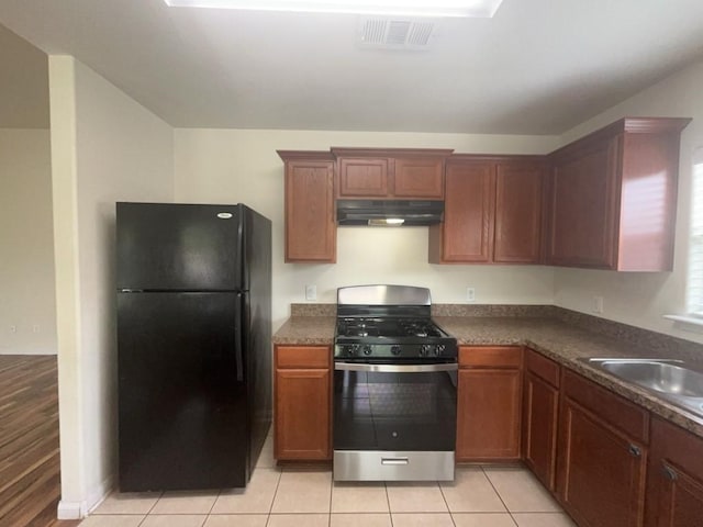 10009 Iron Ridge Dr, Fort Worth, TX 76140 - kitchen with freestanding refrigerator, stainless steel range with gas stovetop, under cabinet range hood, dark countertops, and a sink