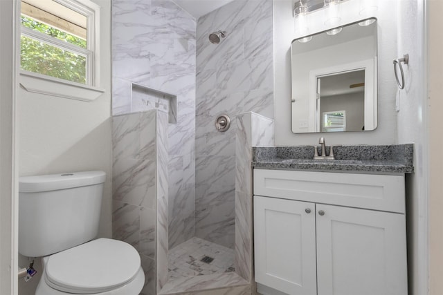 bathroom with tiled shower, vanity, and toilet