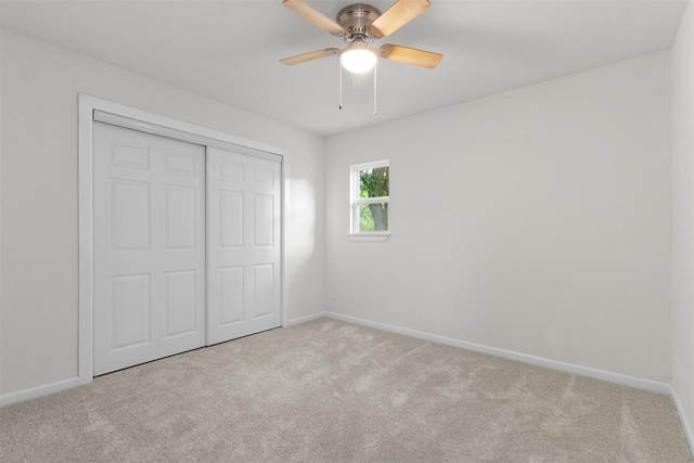 unfurnished bedroom with carpet flooring, baseboards, a closet, and ceiling fan