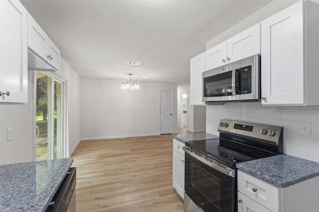 kitchen featuring appliances with stainless steel finishes, a chandelier, tasteful backsplash, light wood finished floors, and white cabinets