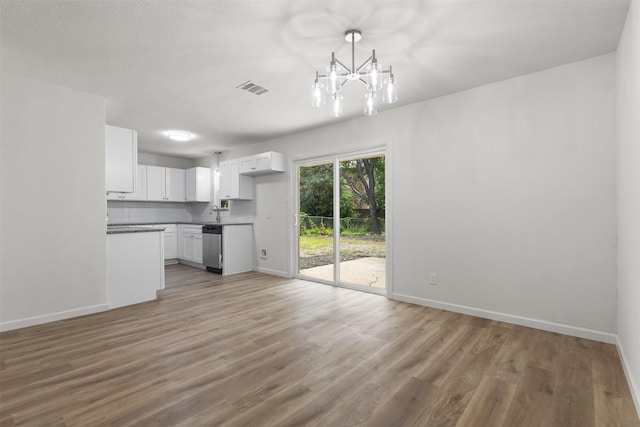 unfurnished dining area featuring a chandelier, baseboards, and light wood finished floors
