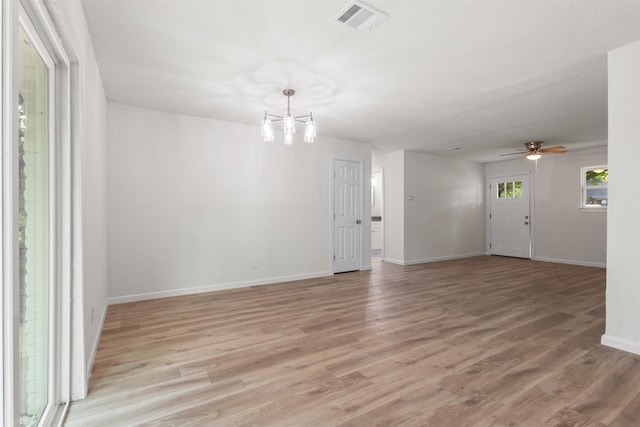 spare room with a chandelier, light wood-style floors, baseboards, and ceiling fan