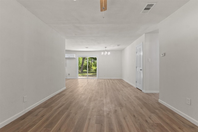 empty room with a chandelier, baseboards, and wood finished floors