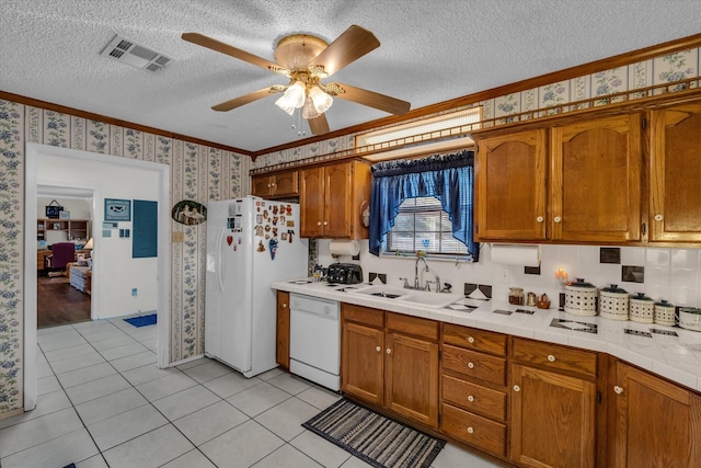 kitchen with white appliances, crown molding, wallpapered walls, a textured ceiling, and a sink