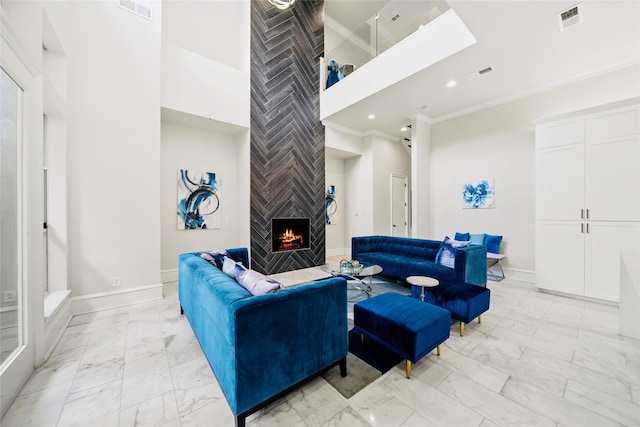 living area with light marble finish flooring, a large fireplace, ornamental molding, baseboards, and a high ceiling