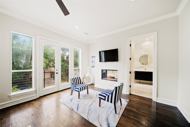 living area with crown molding, french doors, a glass covered fireplace, ceiling fan, and wood finished floors