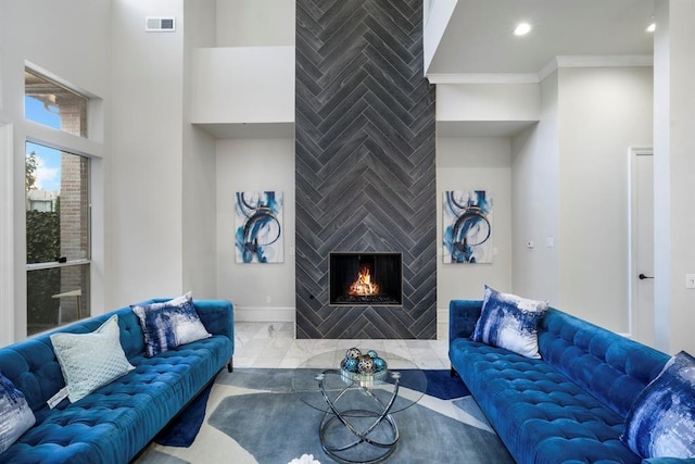 living room with a tiled fireplace, marble finish flooring, baseboards, ornamental molding, and recessed lighting