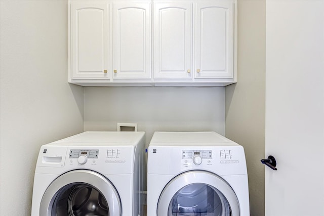 clothes washing area featuring separate washer and dryer and cabinet space