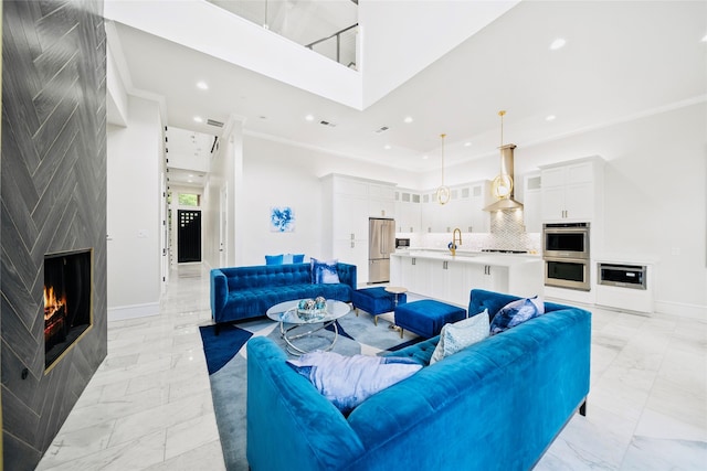 living area featuring light marble finish floors, baseboards, recessed lighting, a large fireplace, and a high ceiling