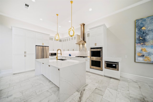 kitchen featuring stainless steel appliances, a sink, light marble finish floors, wall chimney exhaust hood, and white cabinets