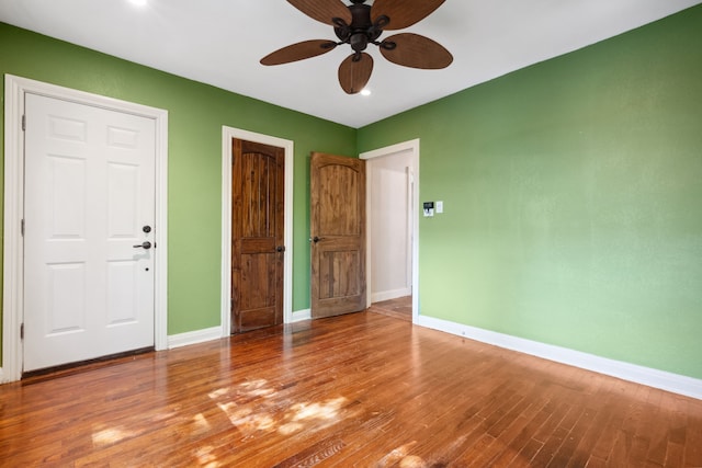empty room featuring baseboards, wood finished floors, and ceiling fan