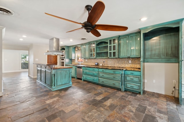 kitchen with green cabinetry, island exhaust hood, appliances with stainless steel finishes, stone tile flooring, and backsplash
