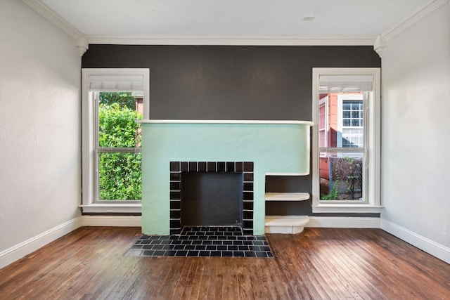 unfurnished living room featuring wood finished floors, crown molding, baseboards, and a fireplace