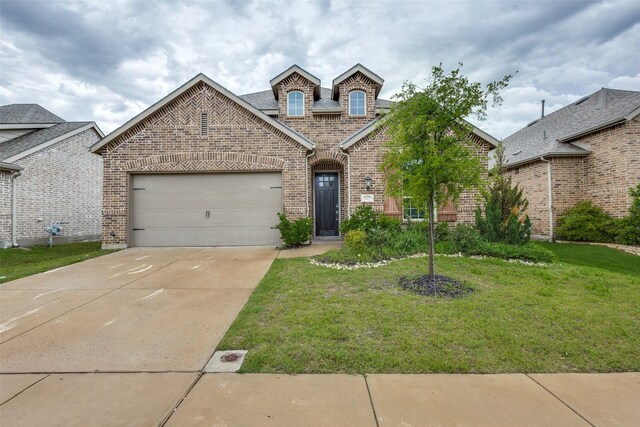 french country inspired facade with brick siding, a front lawn, concrete driveway, and an attached garage