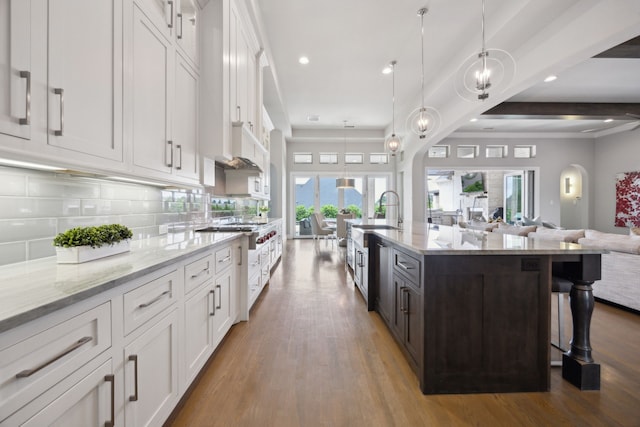 kitchen with open floor plan, a sink, arched walkways, white cabinetry, and recessed lighting