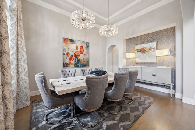 dining room featuring arched walkways, a chandelier, wood finished floors, baseboards, and ornamental molding