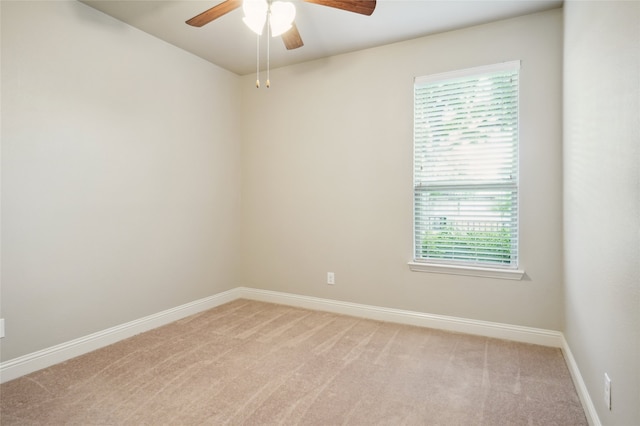 empty room with a ceiling fan, light carpet, and baseboards