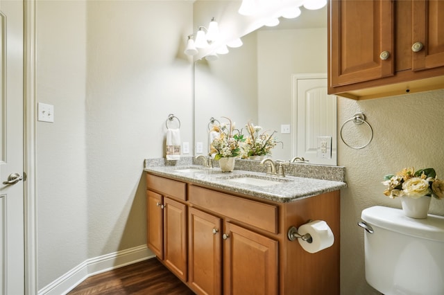 bathroom featuring wood finished floors, toilet, and double vanity