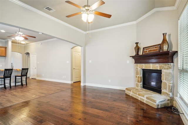 living room with a ceiling fan, arched walkways, wood finished floors, ornamental molding, and a fireplace