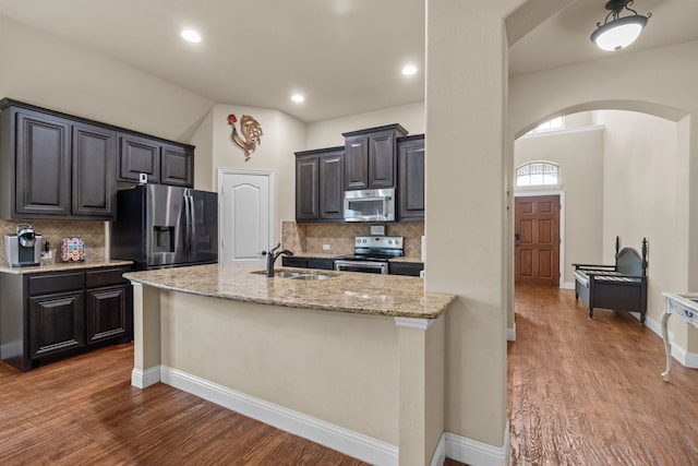 2026 Bay Laurel Dr, Weatherford, TX 76086 - kitchen featuring appliances with stainless steel finishes, arched walkways, a sink, backsplash, and light wood-style flooring