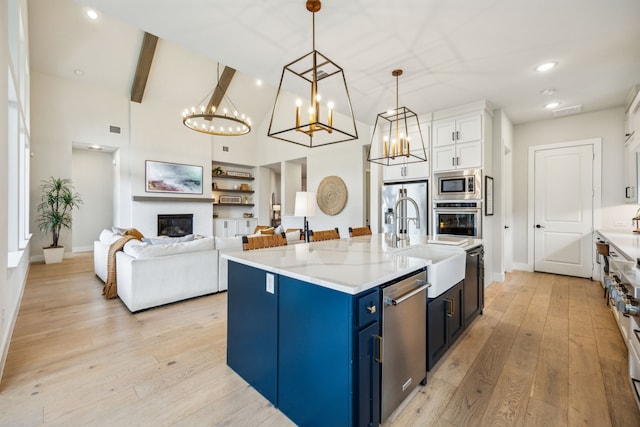 4141 Splitrock Dr, Prosper, TX 75078 - kitchen featuring appliances with stainless steel finishes, blue cabinetry, a sink, light wood-type flooring, and light countertops