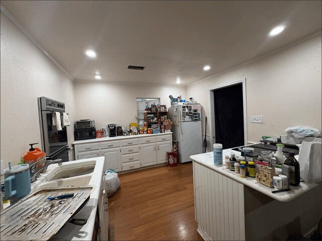 8207 Double Bridge Rd, Mabank, TX 75156 - kitchen with freestanding refrigerator, white cabinets, wood finished floors, light countertops, and crown molding