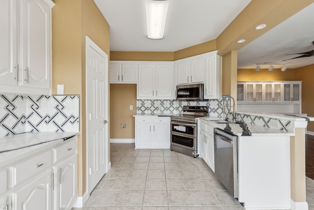 9434 Abbey Rd, Irving, TX 75063 - kitchen featuring appliances with stainless steel finishes, a peninsula, white cabinets, and tasteful backsplash