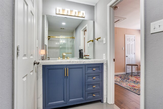 7200 Randall Way, Plano, TX 75025 - bathroom with wood finished floors, a shower stall, vanity, and a textured wall