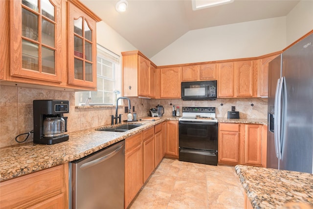 kitchen featuring appliances with stainless steel finishes, a sink, vaulted ceiling, backsplash, and glass insert cabinets