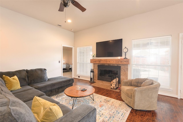 living area featuring a ceiling fan, a fireplace with flush hearth, dark wood-style floors, and baseboards