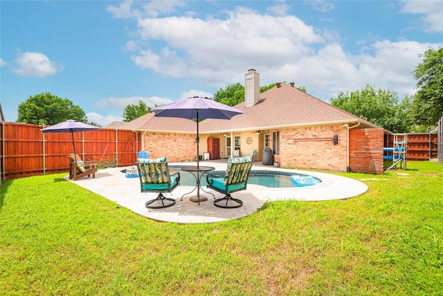 rear view of property featuring a chimney, a patio area, brick siding, and a shingled roof