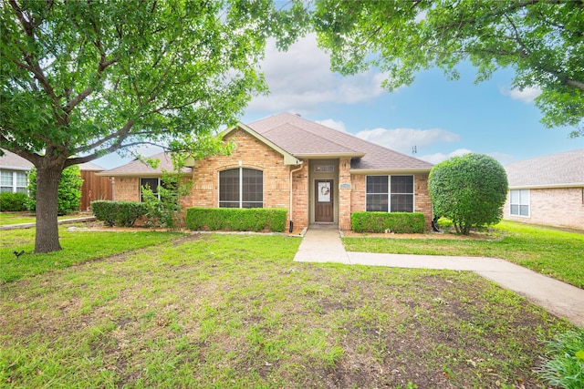 single story home with a front yard, brick siding, and roof with shingles