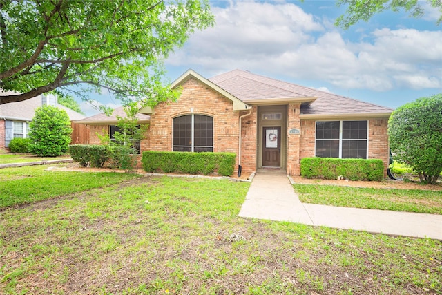 single story home featuring a front lawn, brick siding, and a shingled roof