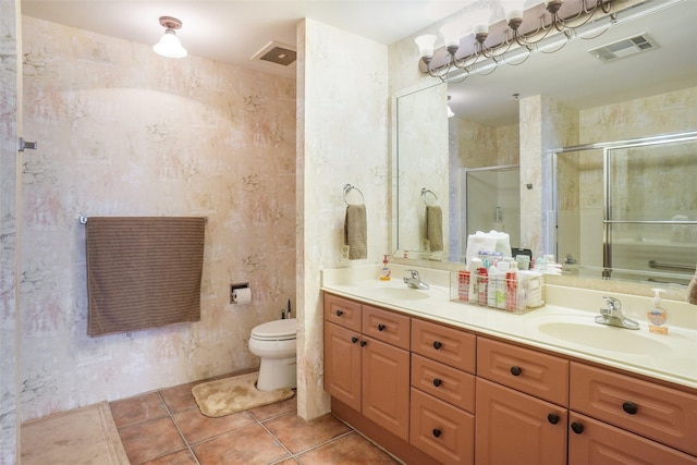 bathroom with a stall shower, double vanity, tile patterned floors, and toilet