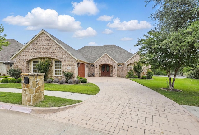 9008 Reata W Dr, Benbrook, TX 76126 - french country home featuring decorative driveway, brick siding, an attached garage, a front yard, and a shingled roof