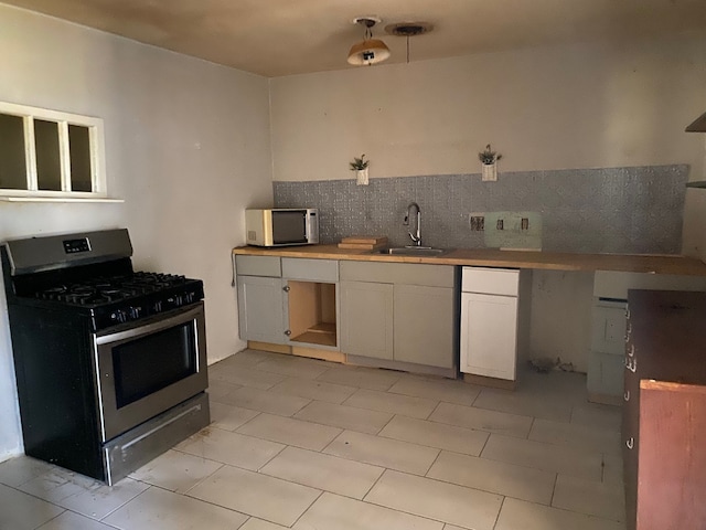 501 S Clay St, Henrietta, TX 76365 - kitchen featuring stainless steel appliances, a sink, white cabinetry, decorative backsplash, and light tile patterned flooring